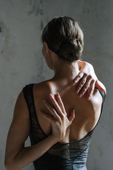 一名穿着黑色背心、双手背在身后伸展身体的女人的背影