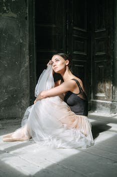 在阳光明媚的房间里，芭蕾舞演员穿着芭蕾舞短裙和黑色背心，优雅地坐着