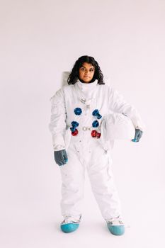 这是一幅年轻女子的肖像，她身着太空服，手持头盔，非常适合太空、角色扮演和服装主题
