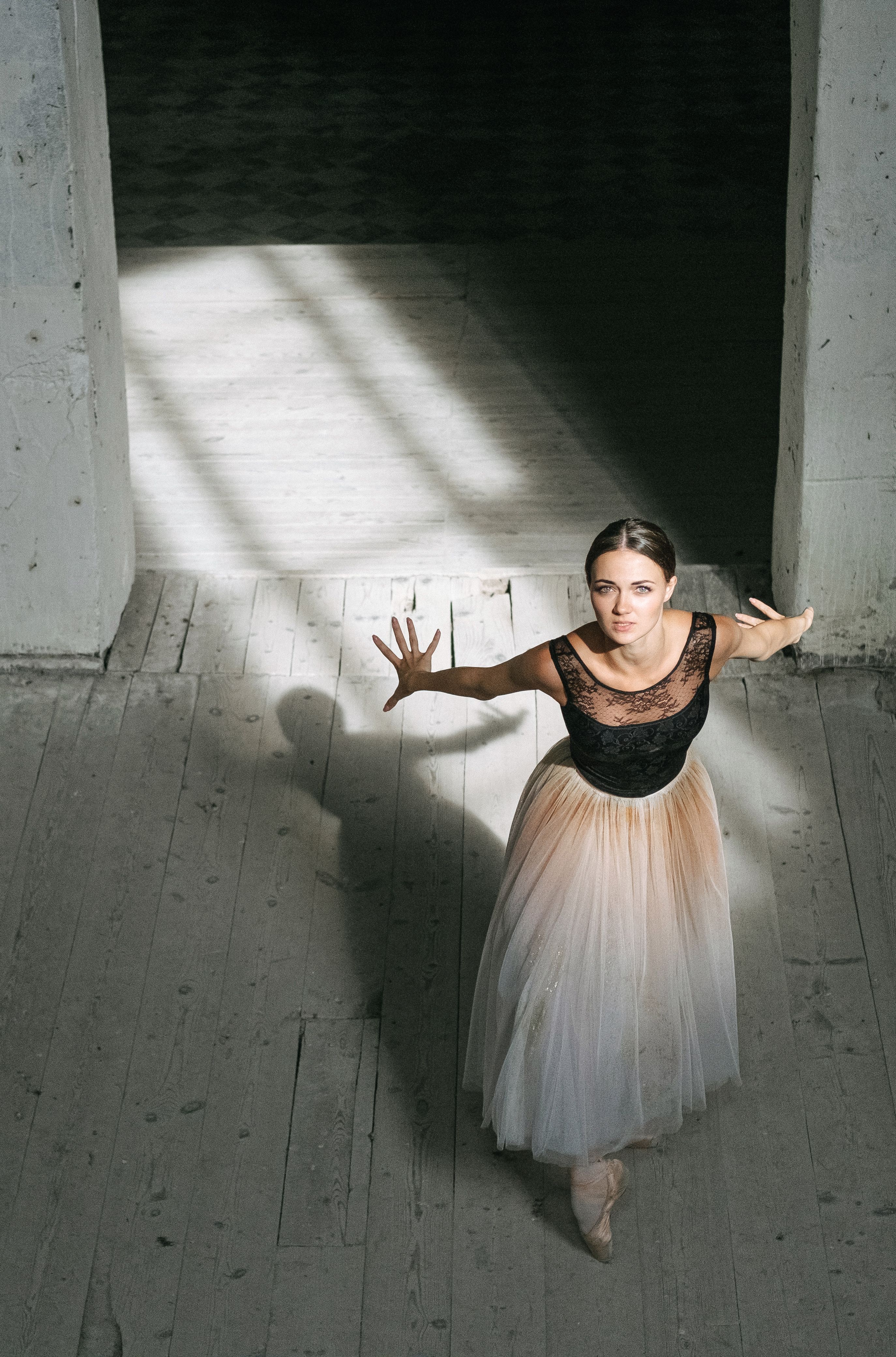Ballet dancer performing an elegant pose in natural light indoors, showcasing grace and beauty.