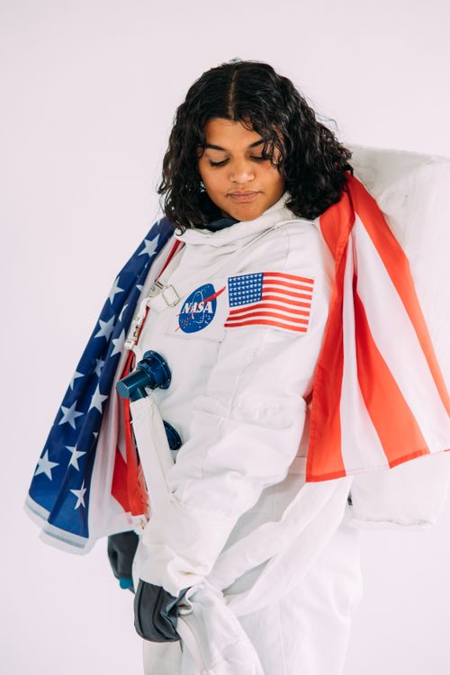 Free Portrait of a woman in a NASA astronaut costume holding an American flag. Stock Photo