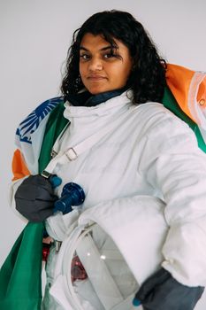 一位自信的南亚女性身着宇航服，手举印度国旗，传递着赋权与多样性的信息
