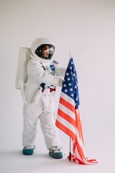 女宇航员在室内穿着全套宇航服与美国国旗合影