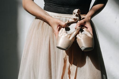 Free Close-up of a ballet dancer holding worn pointe shoes, showcasing dedication and artistry. Stock Photo