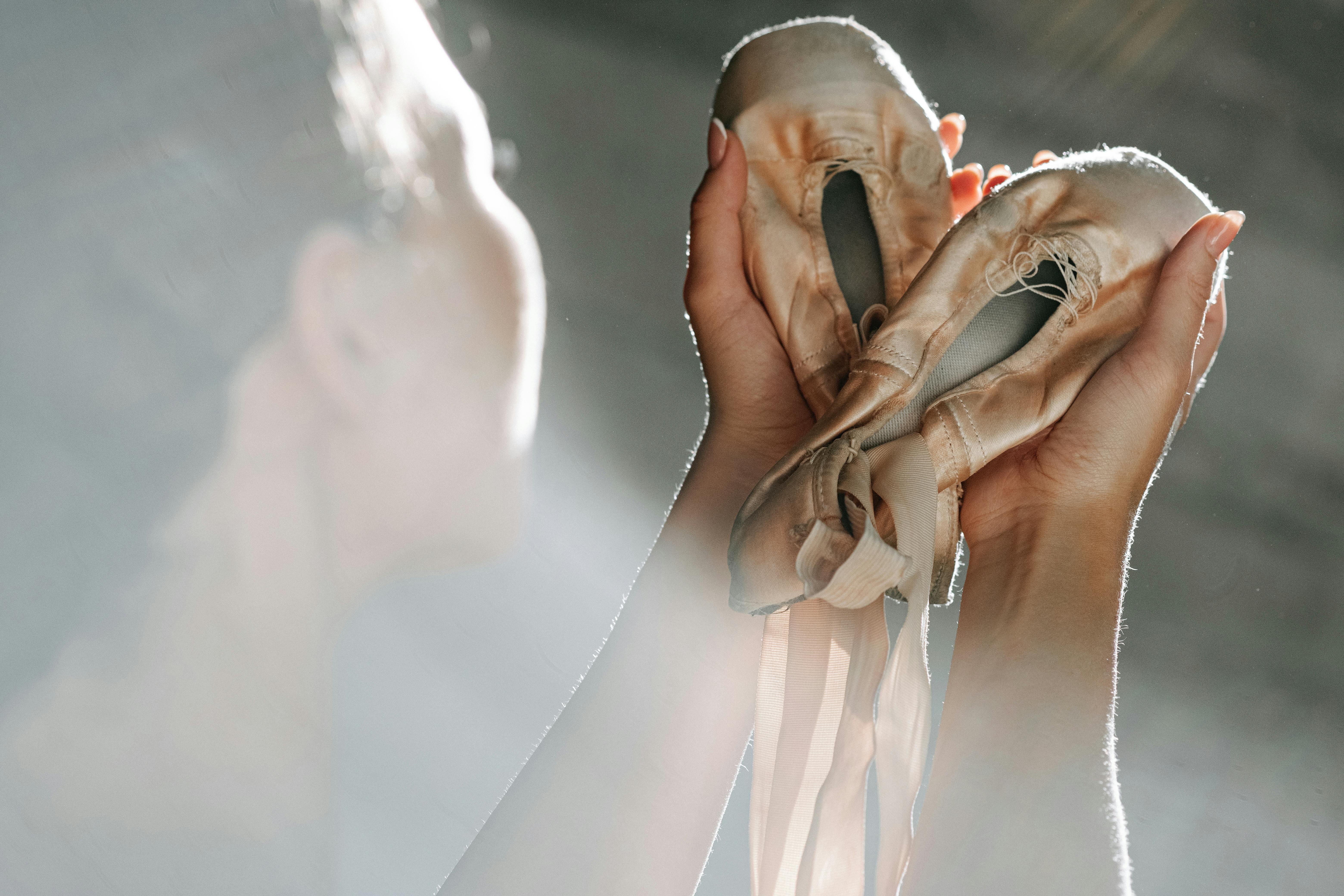 Free Artistic shot of a ballerina holding worn ballet shoes, highlighting grace and dedication. Stock Photo