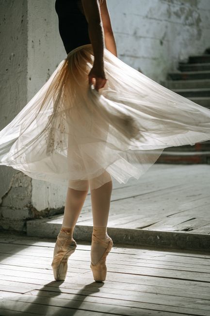 Ballet dancer in a tutu performing gracefully on pointe indoors.