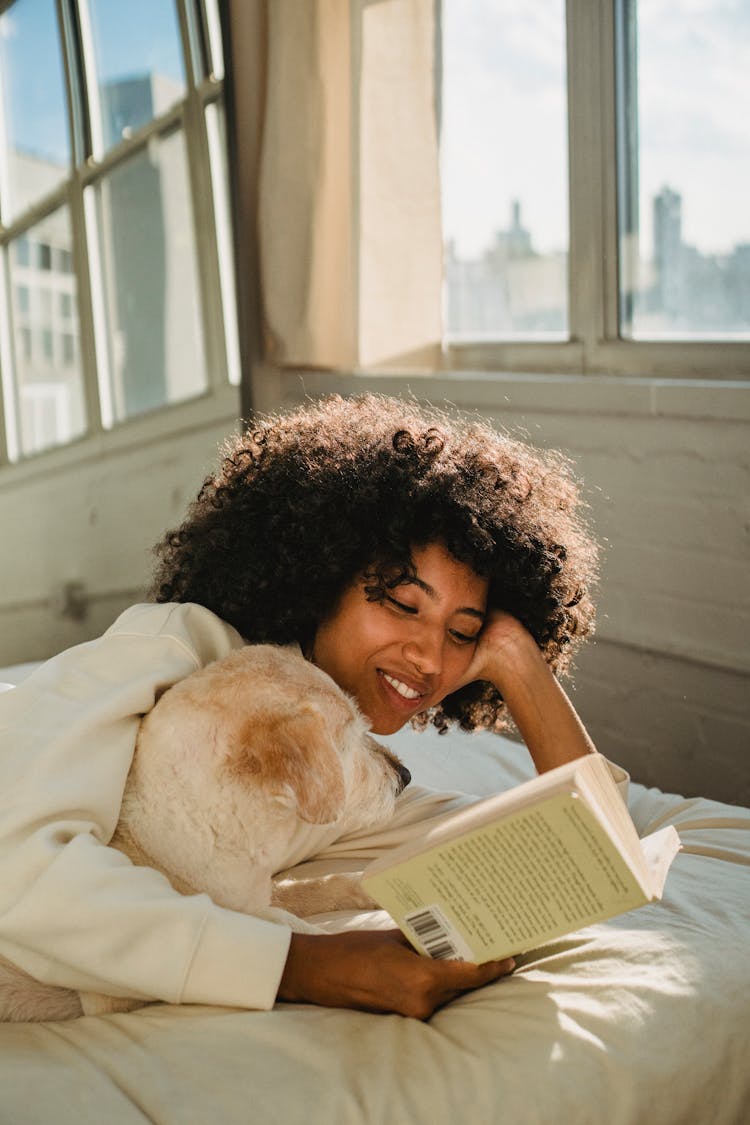 A Woman Reading A Book With Her Dog 