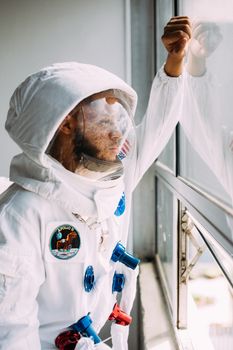 身穿阿波罗太空服的男子透过窗户凝视，唤起了探索的渴望