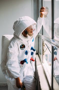 一名男子穿着受美国宇航局启发的太空服，望着窗外沉思