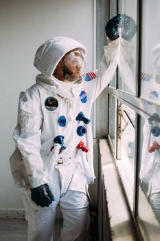 宇航员穿着宇航服，透过窗户凝视远方，激发了人们的好奇心和探索欲