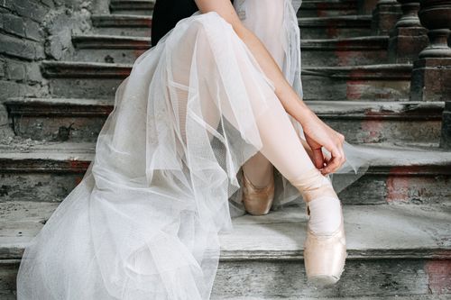 Free Ballerina in pointe shoes sitting gracefully on an old staircase in a delicate tutu. Stock Photo
