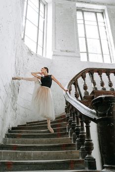 Ballet dancer in a graceful pose on a classic spiral staircase in a bright, serene setting.