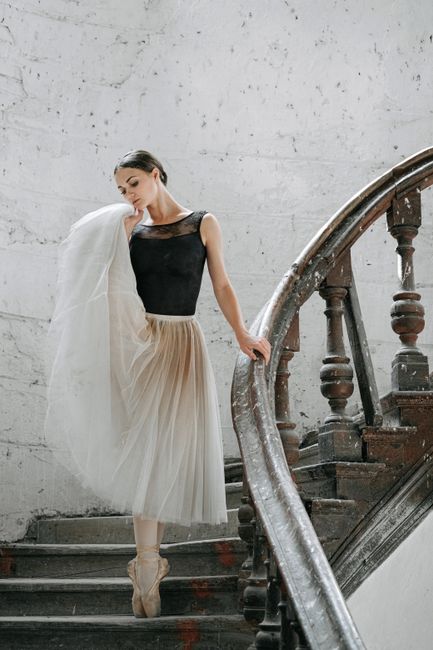 Ballet dancer in a classic pose on an old staircase, exuding elegance and grace.