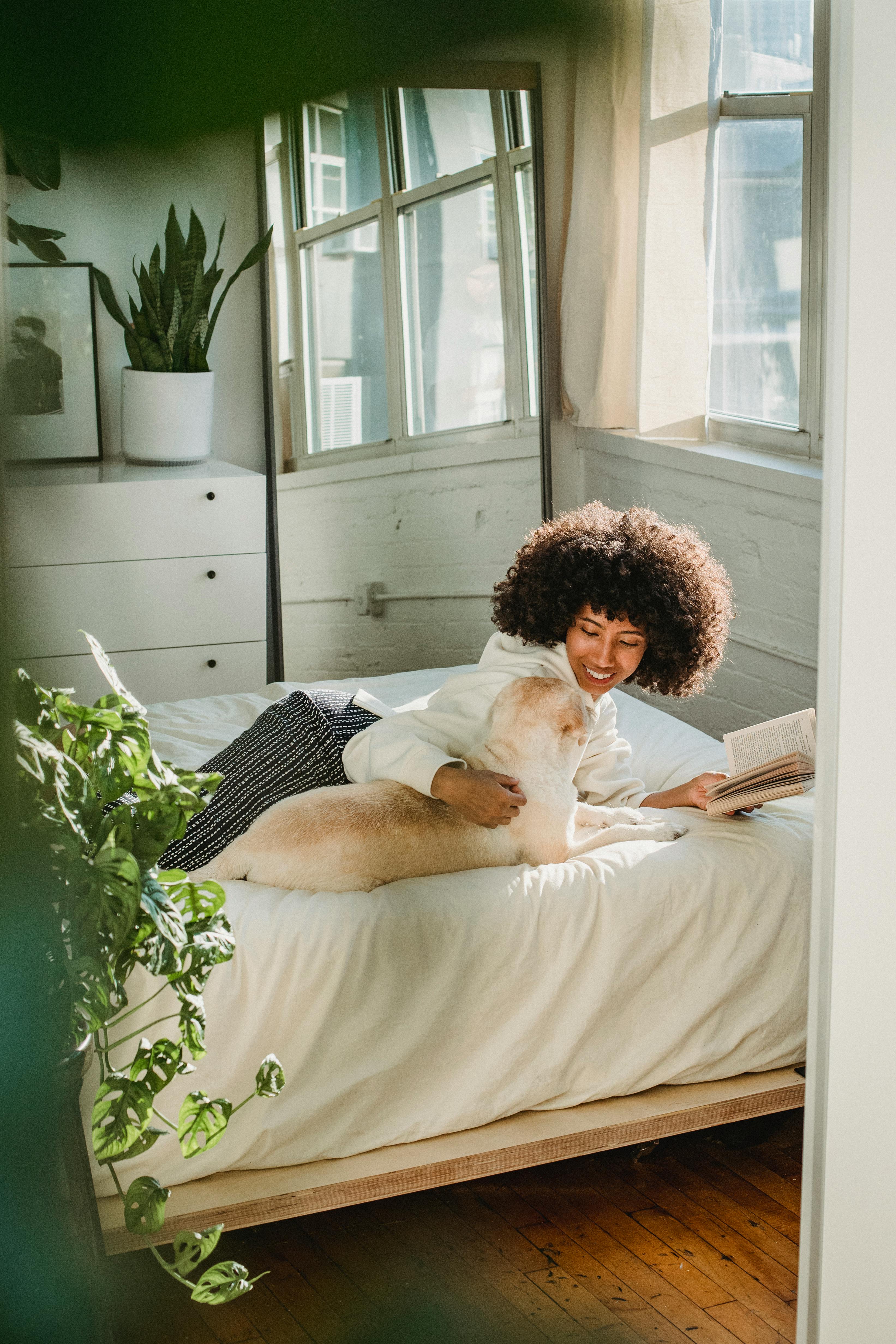 cheerful black woman enjoying weekend with book and pet