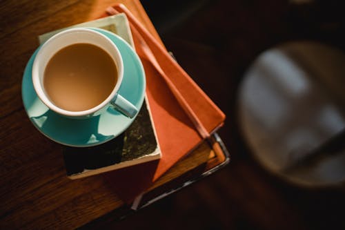 From above of ceramic cup of hot aromatic coffee placed on book and notepad