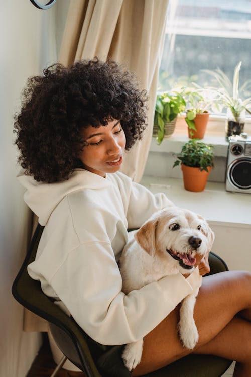 Black woman hugging funny puppy sitting at home