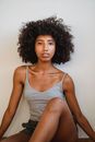 Black woman with curly hair against white wall