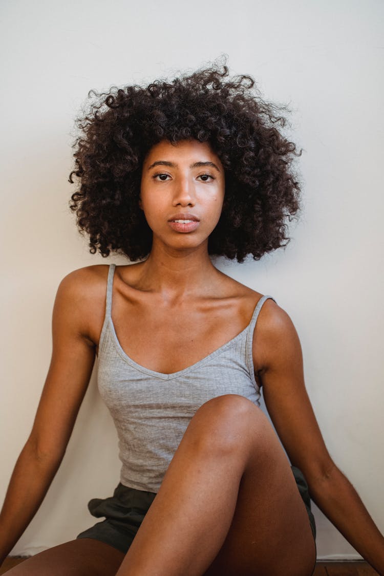 Black Woman With Curly Hair Against White Wall