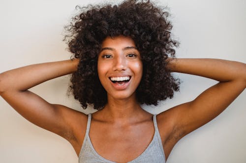 Free Delighted black woman touching hair and looking at camera Stock Photo