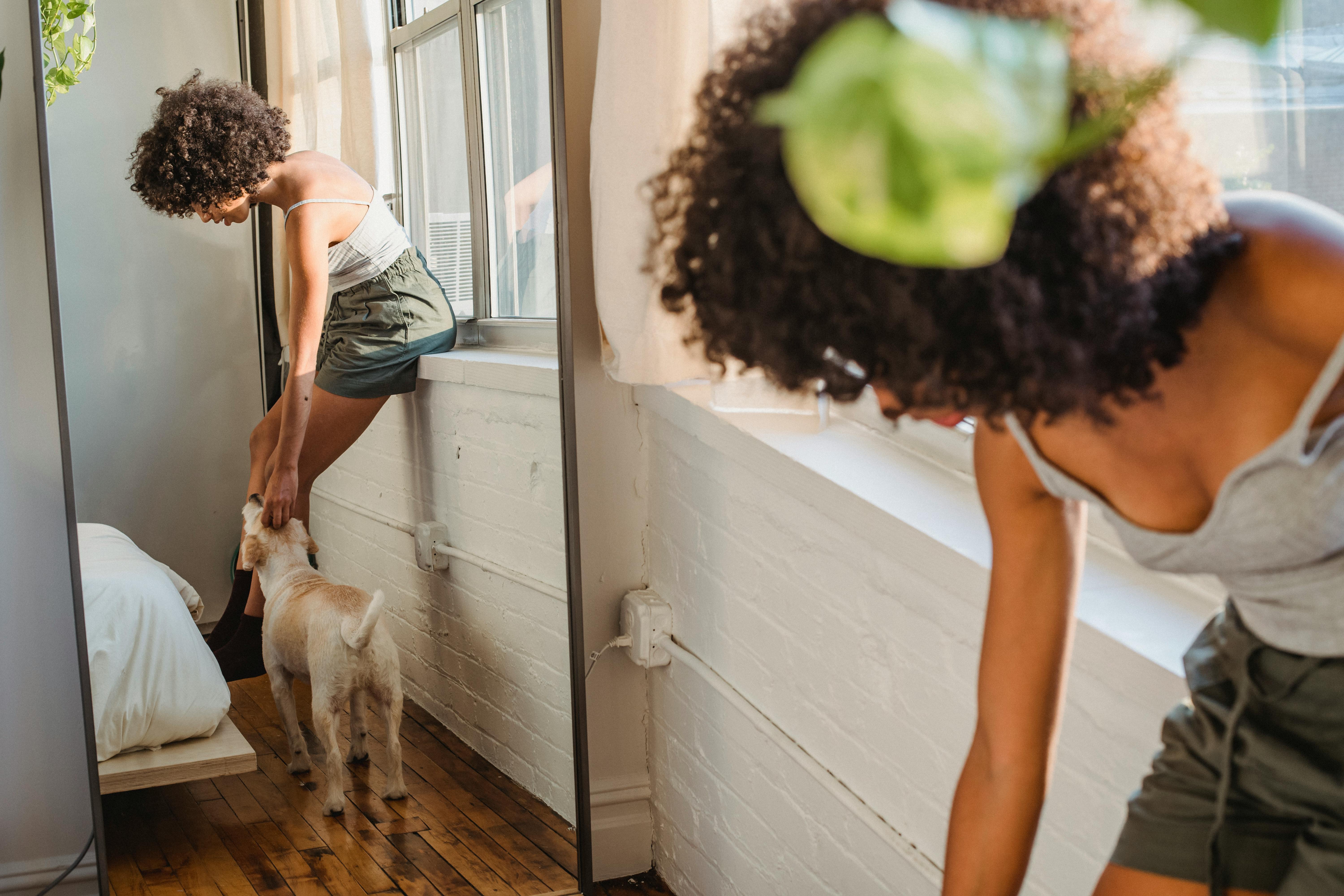 Black woman caressing dog in bedroom