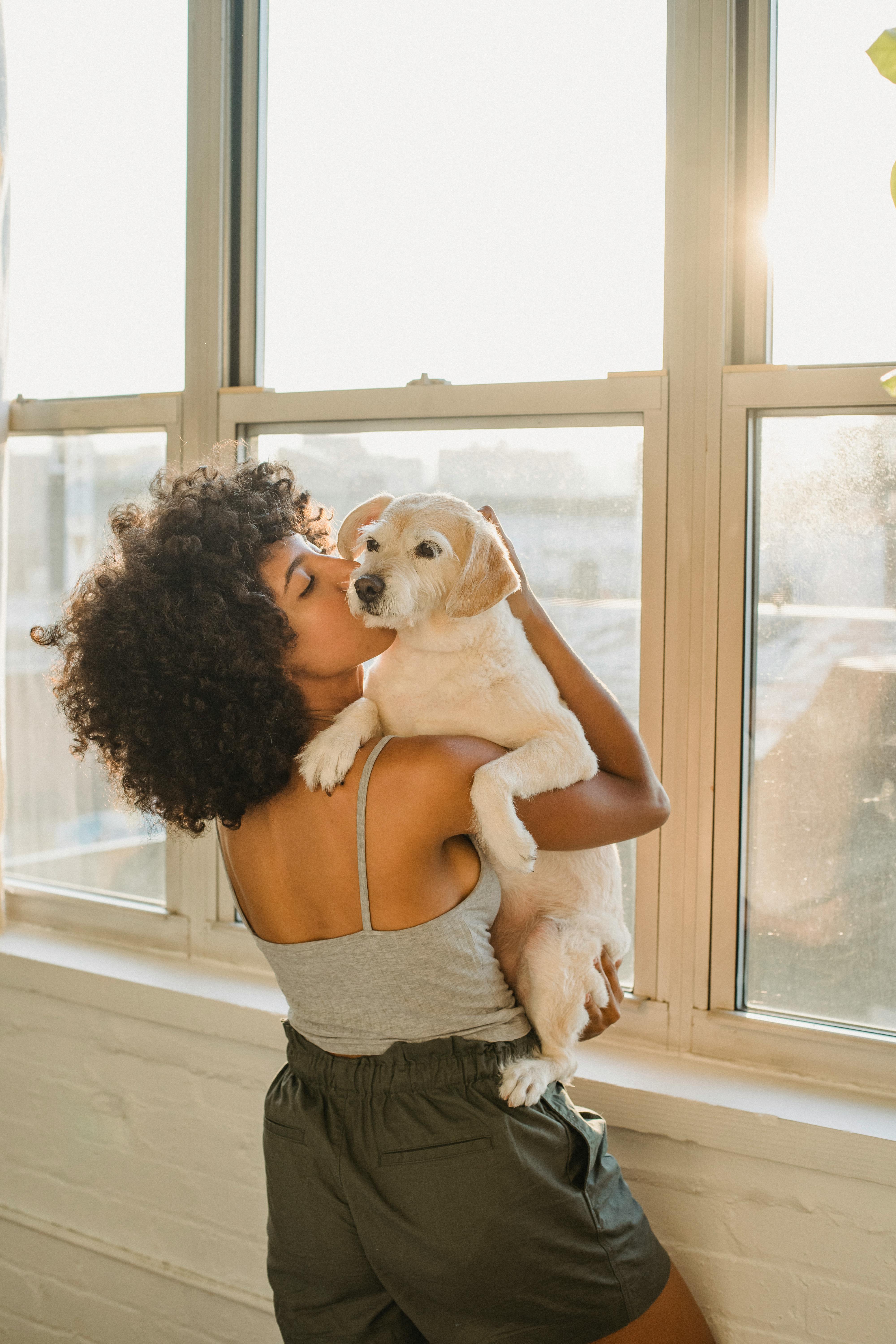 african american woman kissing dog in sunlight