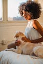 一位非裔美国妇女和她的狗在阳光明媚、舒适的卧室里享受着温暖的时光