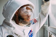 一位穿着美国宇航局太空服的非裔美国男子望向窗外，捕捉到反思与探索的时刻