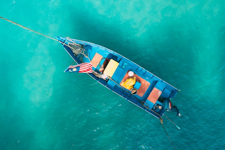 Small Boat With Flag Floating On Water