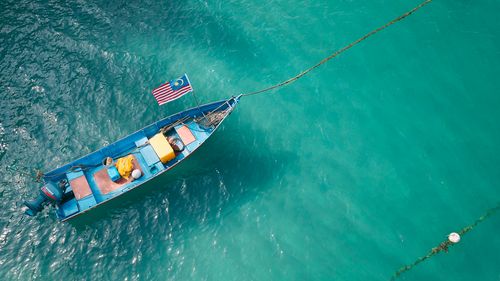 Free High view of small boat with flag of Malaysia floating on rippled water in sunny day Stock Photo