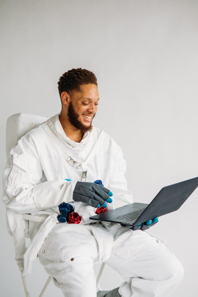 Man In An Astronaut Costume Holding A Laptop