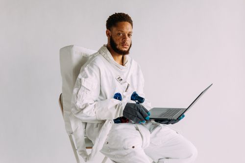 Free A portrait of an astronaut in a space suit holding a laptop, symbolizing technology and exploration. Stock Photo