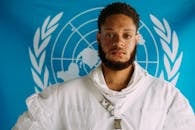 身穿蓝色背景、白色服装的雀斑男子