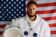 一名身穿宇航员服的男子站在美国国旗背景前，展现了太空主题的灵感