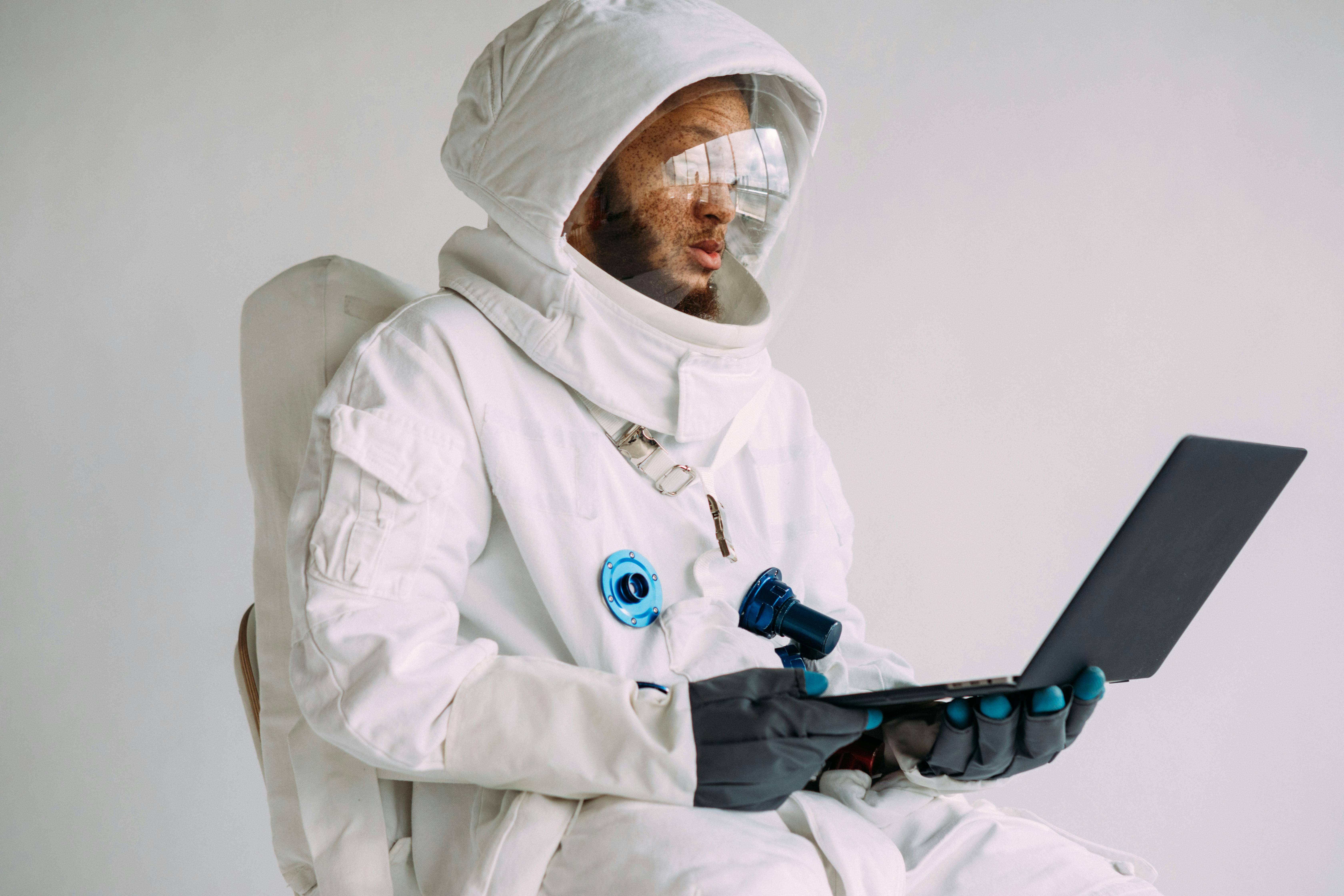 一名宇航员身着太空服，在室内使用笔记本电脑工作，将技术与探索融为一体