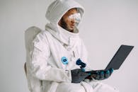 一名宇航员身着太空服，在室内使用笔记本电脑工作，将技术与探索融为一体