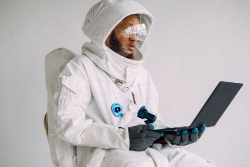 Free An astronaut in a space suit working on a laptop indoors, blending technology and exploration. Stock Photo