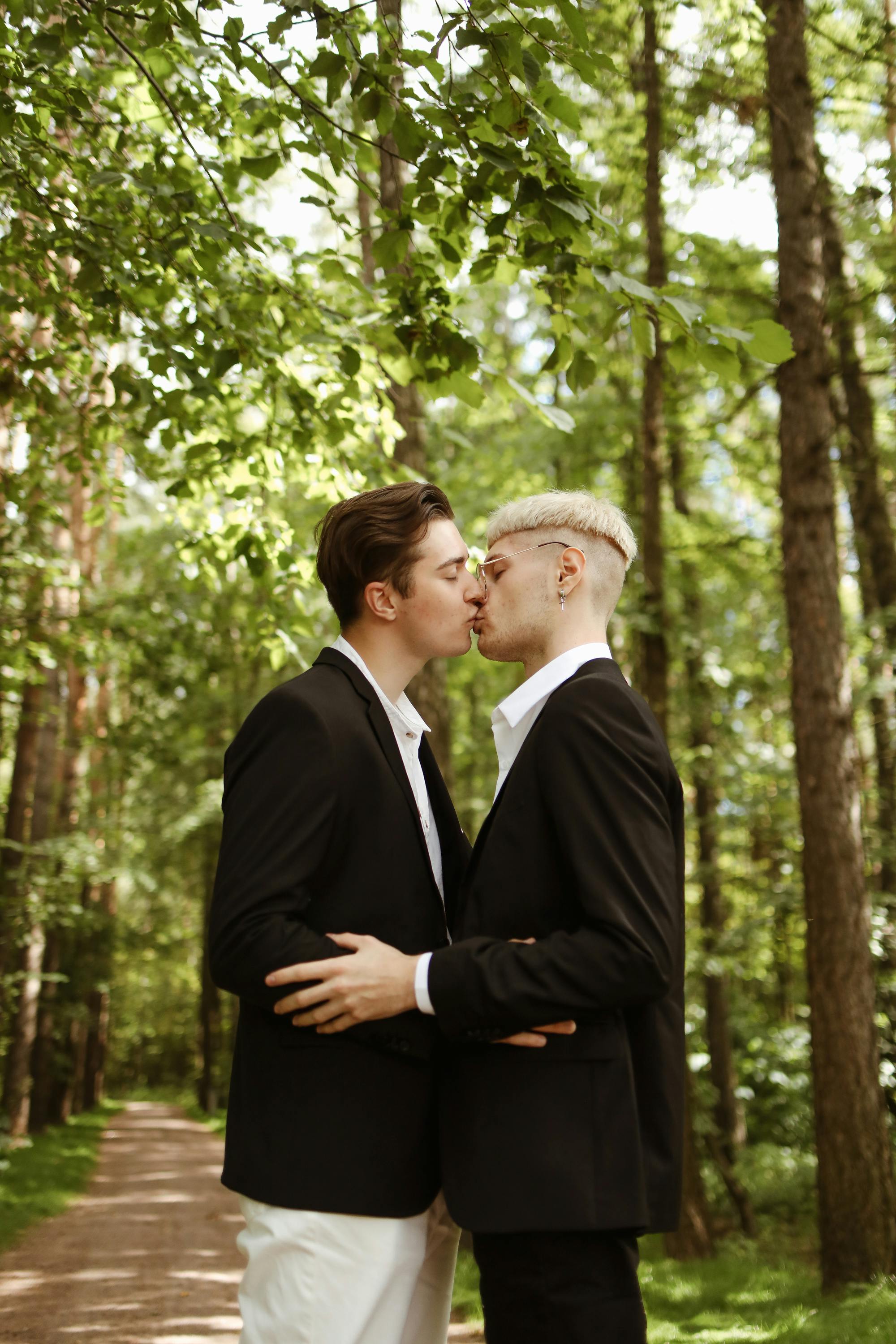 young men standing in black coat kissing each other