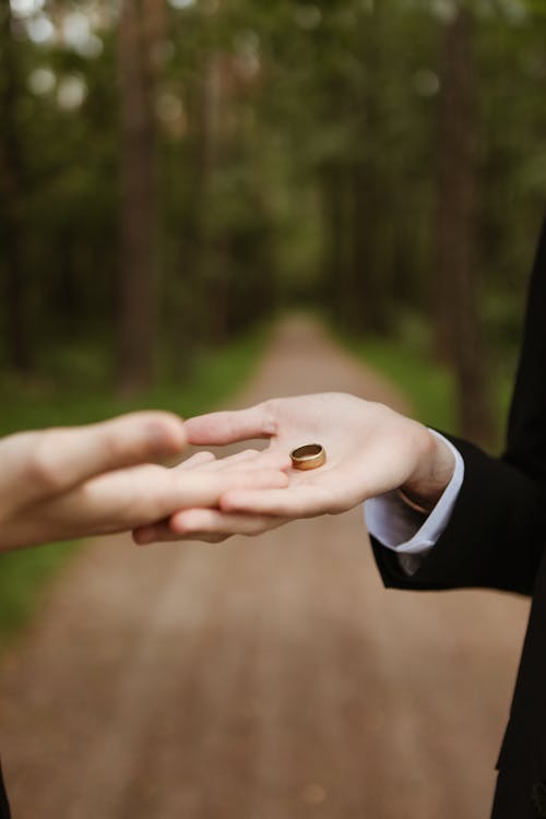 Hand Holding a Gold Round Ring