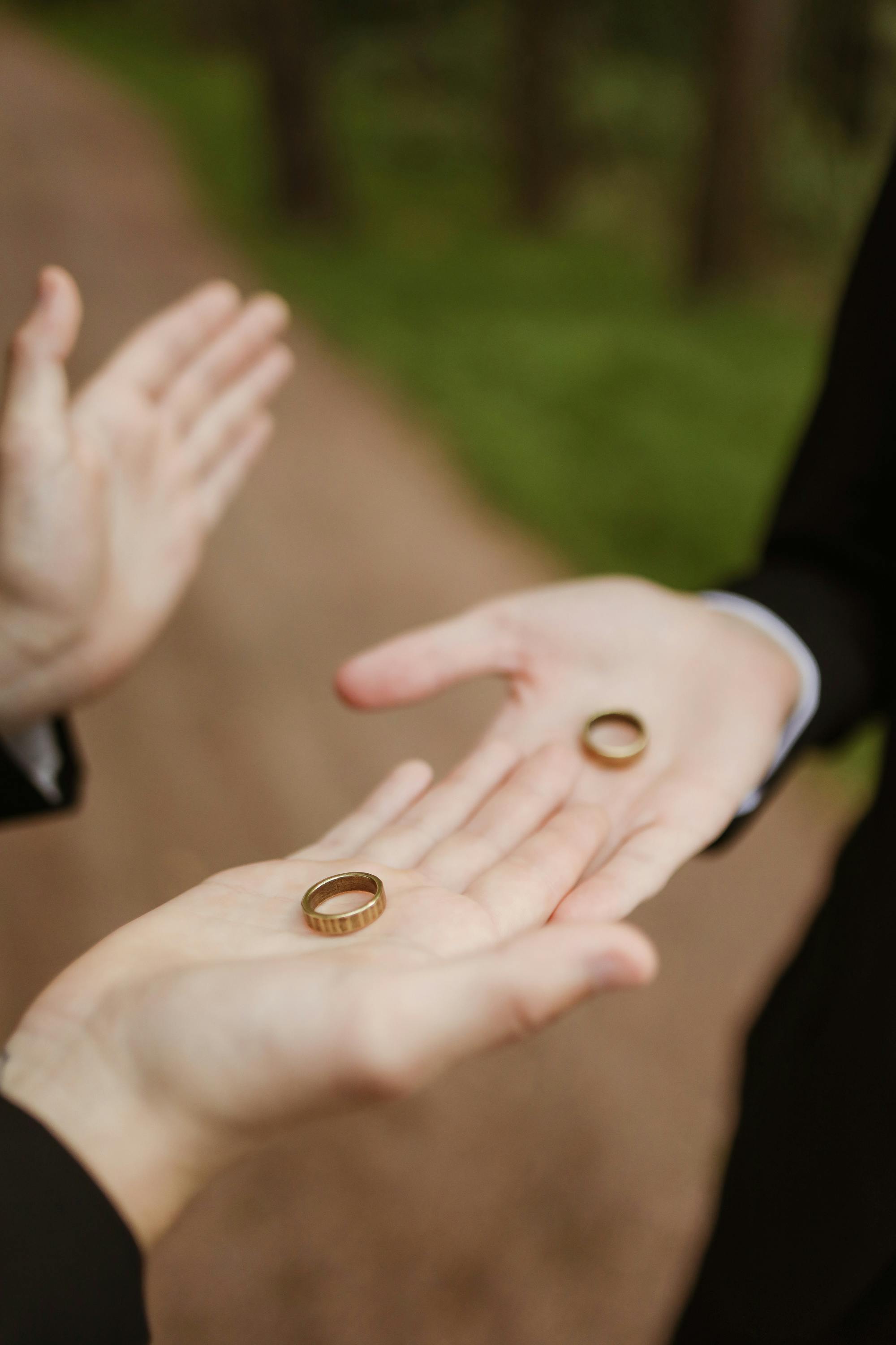 Close-up of hands exchanging wedding rings, symbolizing love and commitment in LGBTQ+ engagement.
