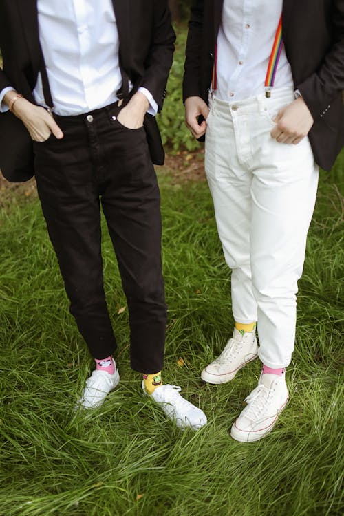 Two People Wearing Black and White Pants Standing on Grass