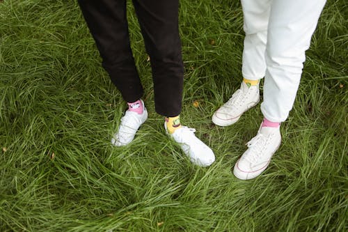 Two People Wearing Black and White Pants Standing on Grass