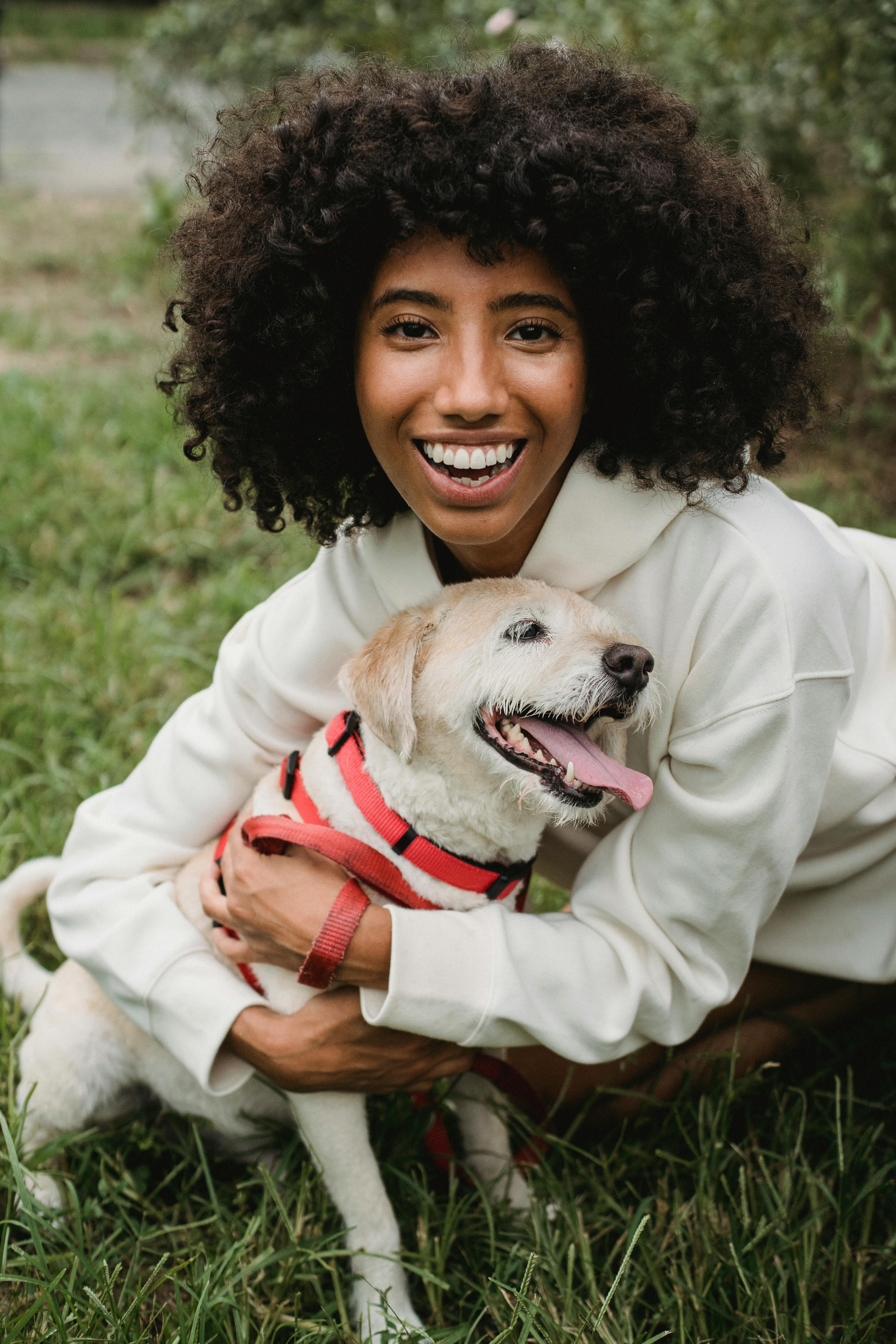 happy black woman hugging dog on street