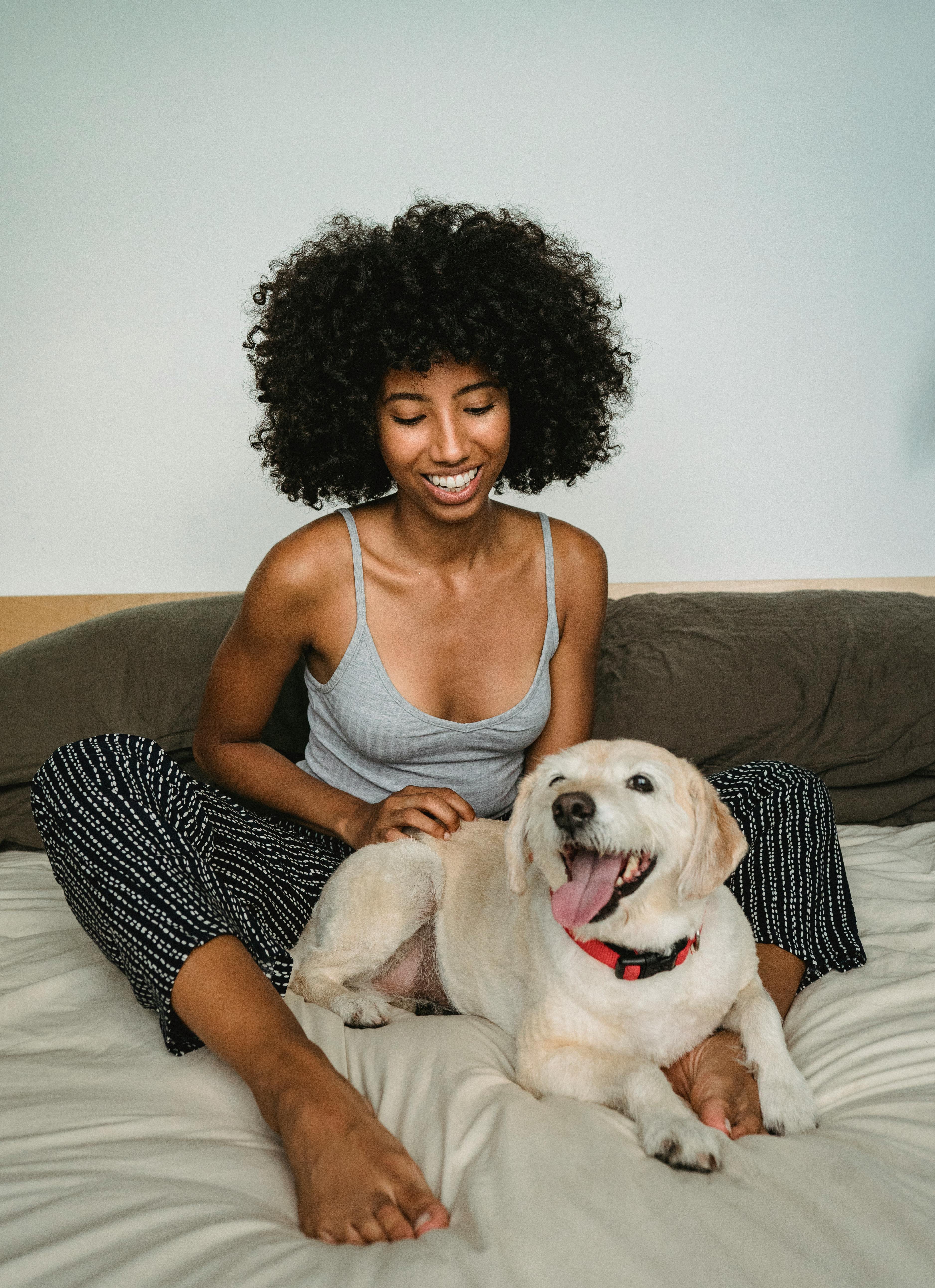 一位穿着休闲装的女士在室内微笑着，和她顽皮的狗一起享受美好时光
