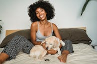 一位穿着休闲服、面带微笑的非裔美国女性，在舒适的卧室里与小狗在一起，不寒而栗