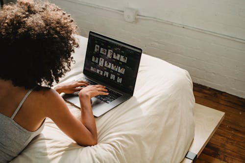 Free Black woman working on laptop in bedroom Stock Photo