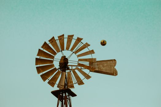 Windmill with ball flying in clear blue sky. Rustic and vintage feel, ideal for outdoor and summer themes.