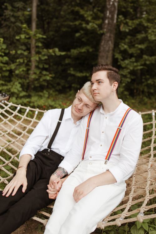 Free Two men holding hands in a hammock outdoors, symbolizing love and diversity. Stock Photo