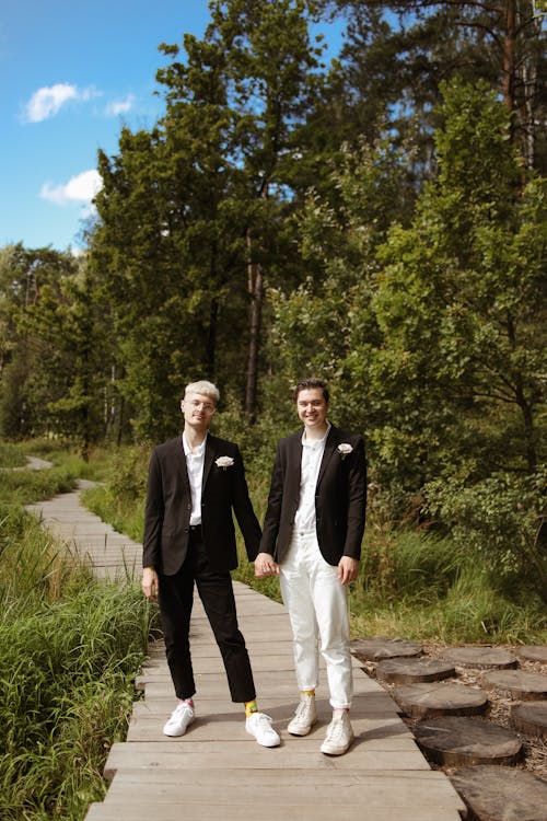 Men in Black Suit Standing on Wooden Pathway