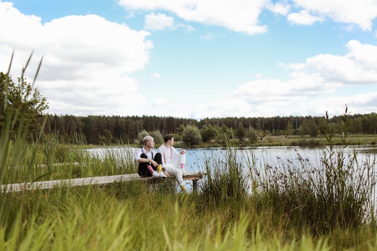 Men Sitting On Wooden Dock Beside The River