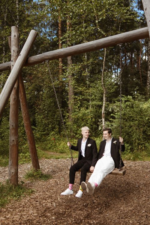 Free Two men in suits enjoying a swing ride, embracing love and nature. Stock Photo